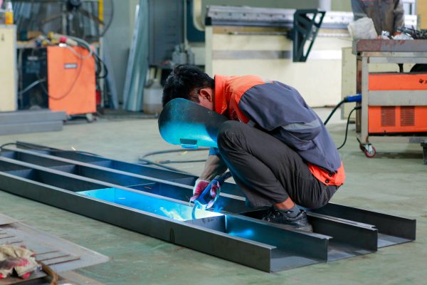 Worker welding a steel frame at the Tan Long workshop.