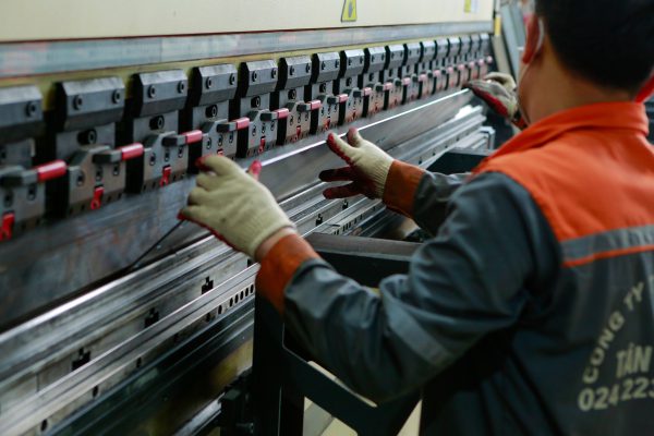 Technician bending a metal sheet with a press brake.